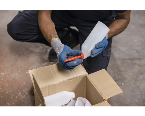 Eine Person setzt eine rote Tülle auf eine leere Kunststoffflasche über einem Karton.