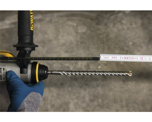 Messung der Bohrtiefe mit einem Zollstock an einer Bohrmaschine mit Bohrer