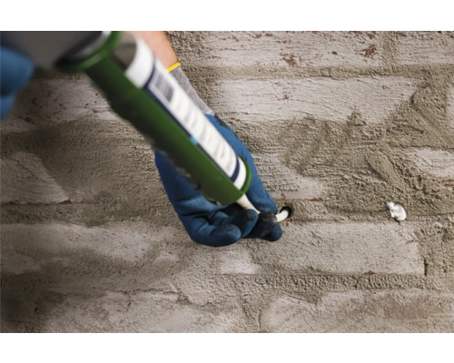 Handwerker füllt ein Loch in einer Steinwand mit Dichtmasse