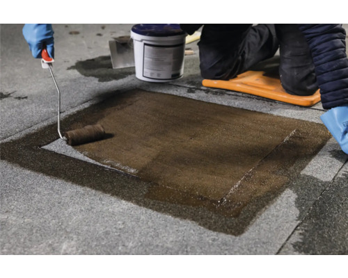 Auftragen von Abdichtung mit einer Farbwalze auf einer Dachfläche.