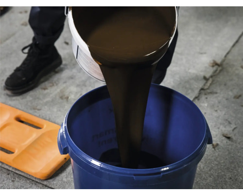 Flüssiger Abdichtstoff wird in einen blauen Eimer gegossen