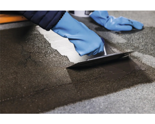 Handwerker repariert einen Boden mit einer Spachtel und einer Bodenbeschichtung.