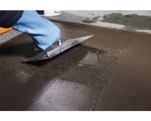 Auftragen von Bodenausgleichsmasse mit einer Glättkelle