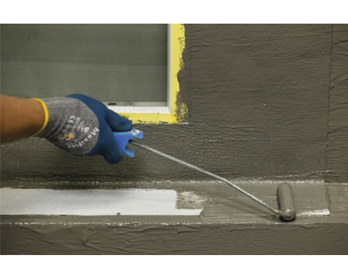 Eine Person trägt eine Schutzschicht mit einer Farbwalze auf eine Oberfläche auf