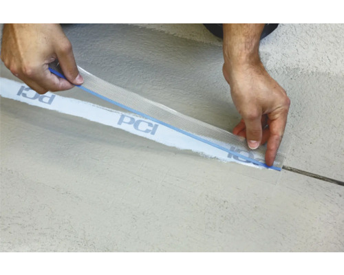 Ein Arbeiter bringt ein Dichtband der Marke PCI an einer Wand an.