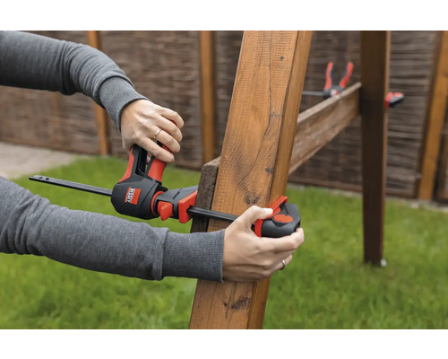 Eine Person verwendet eine Einhandzwinge von Bessey, um Holz zusammenzuzwingen.