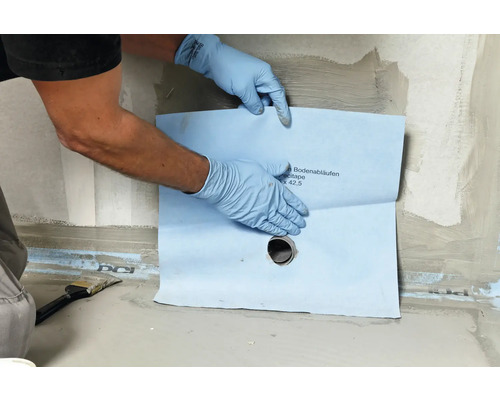 Detailaufnahme der Montage eines Dichtbandes für Bodenabläufe im Badezimmer