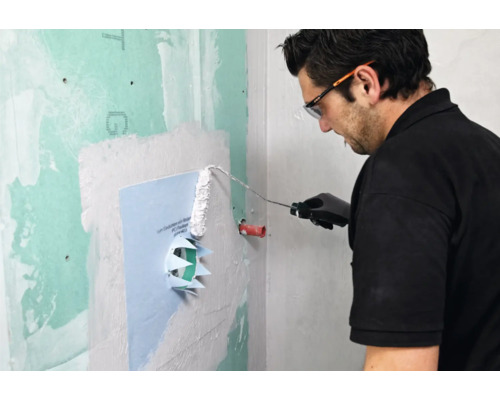 Mann trägt Dichtschlämme mit einer Farbwalze auf Abdichtmanschette auf