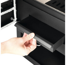 Detailaufnahme eines Kaminofens mit Aschekasten in der Hand