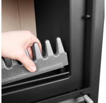 Hand legt Gussrost in den Kaminofen