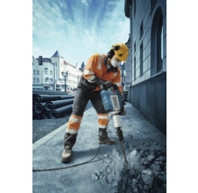 Bauarbeiter benutzt einen Abbruchhammer zur Bearbeitung von Beton auf einer Baustelle
