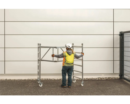 Bauarbeiter schiebt ein fahrbares Gerüst.