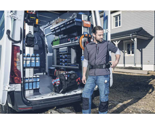 Ein Handwerker steht vor einem Transporter mit Regalsystem zur Werkzeugaufbewahrung.