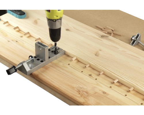 Eine Bohrmaschine bohrt Löcher in ein Holzbrett mit einem Dübelbohrgerät.