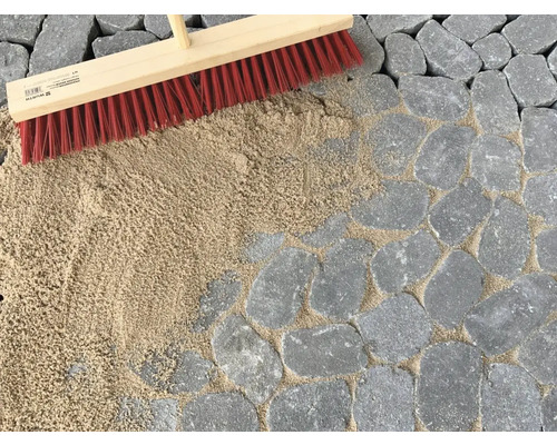 Pflasterfugen werden mit einem Besen und Fugensand verfüllt.