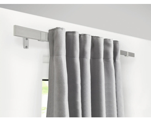 Graue Vorhänge hängen an einer Holzgardinenstange an der Wand