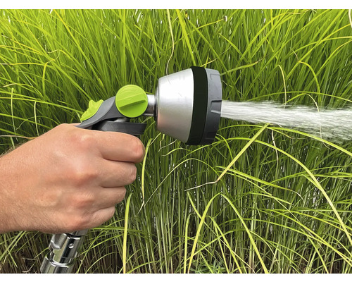 Eine Hand hält eine Gartenspritze, die Wasser versprüht.