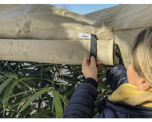 Person befestigt eine Schutzhülle im Außenbereich mit einem Klettverschluss