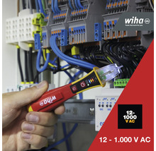 Wiha Logo. Eine Hand hält einen Spannungsprüfer vor einem Verteilerkasten. Der Spannungsprüfer ist für 12 bis 1.000 Volt Wechselspannung geeignet.