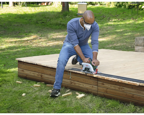 Mann sägt Holzterrasse mit Handkreissäge