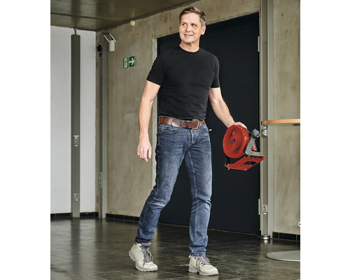 Mann trägt einen Akku-Ventilator in einem Flur.