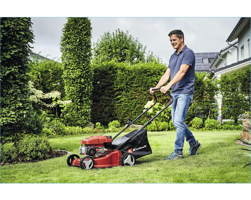 Mann mäht Rasen mit einem Rasenmäher von Einhell im Garten.