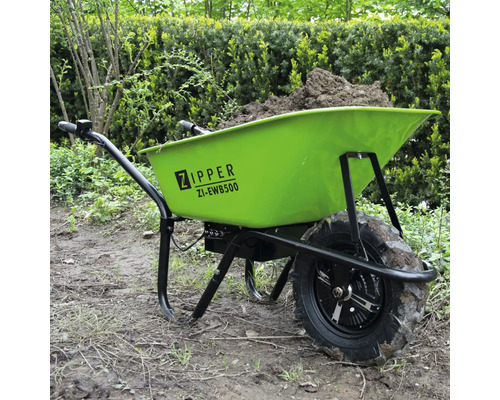 Grüne Schubkarre mit Erdfüllung im Garten