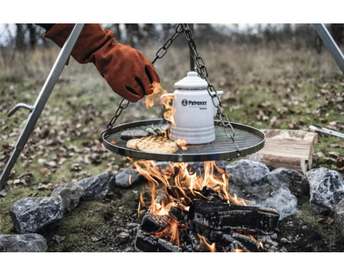Grillplatte mit Speisen, Kessel und Handschuh über offenem Feuer