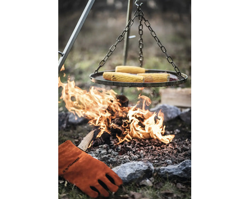 Grill mit Maiskolben über offenem Feuer und Grillhandschuh