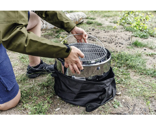 Person montiert tragbaren Grill auf einer Wiese