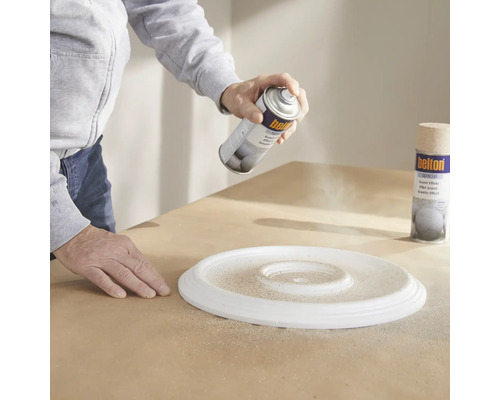 Eine Person sprüht Farbe auf eine Rosette mit einem Graniteffekt-Spray