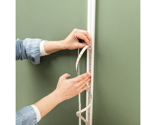 Eine LED-Leiste wird an einem Wandprofil befestigt.