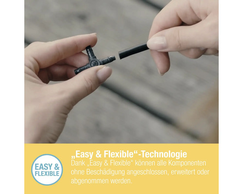 Eine Person verbindet ein T-Stück mit einem Bewässerungsschlauch.