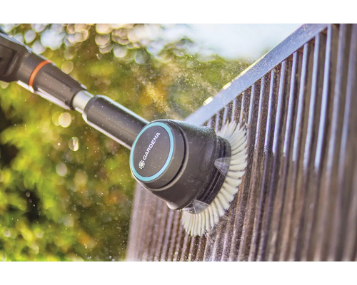 Gardena Bürste reinigt einen Zaun mit Wasser