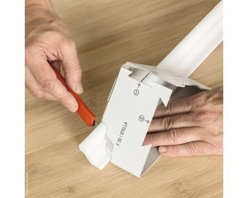 Eine Person schneidet mit einem Universalmesser ein Verpackungsteil.