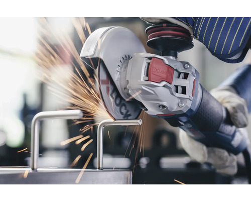 Eine Person schneidet mit einem Winkelschleifer ein Metallstück, wobei Funken entstehen.