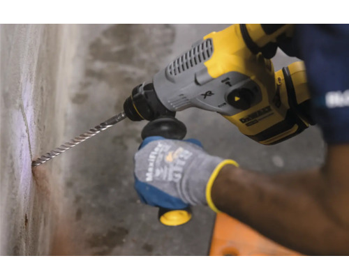 Ein Bediener bohrt mit einem Bohrhammer ein Loch in eine Betonwand.