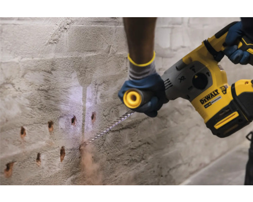 Eine Person bohrt mit einem Bohrhammer Löcher in eine Mauer.