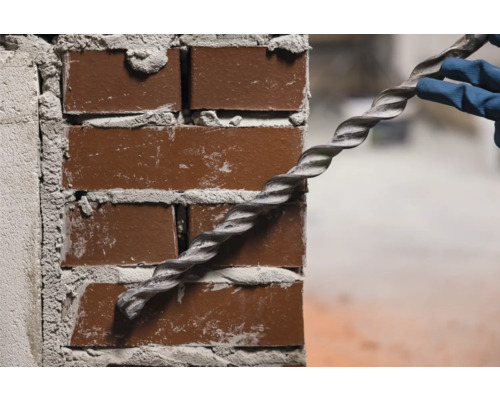 Eine Spiralankerstange wird in eine Ziegelwand eingeführt.