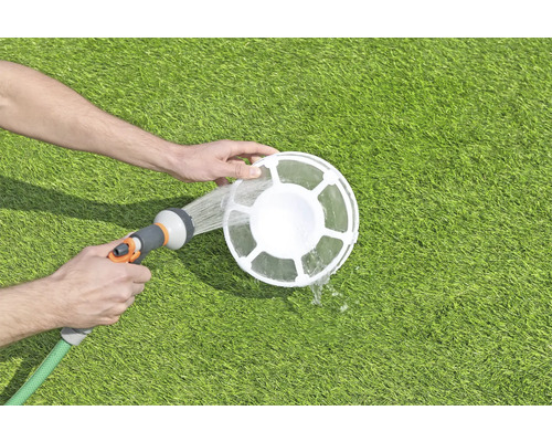 Reinigung eines Poolskimmers mit einem Gartenschlauch auf einer Rasenfläche.