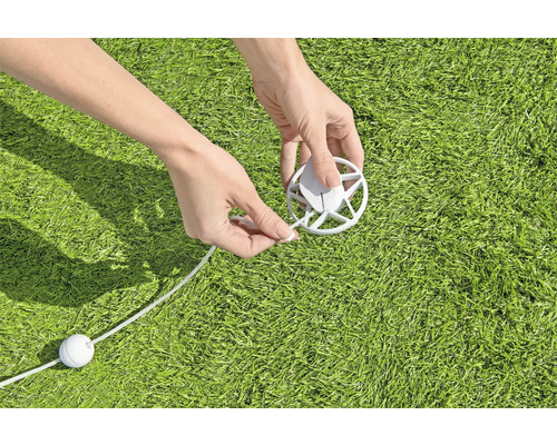 Person befestigt eine Leine an einer Abdeckung auf Rasen