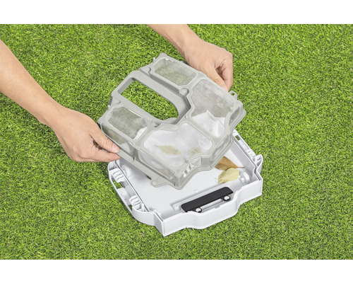 Person setzt Sieb in einen Poolroboter auf grünem Rasen