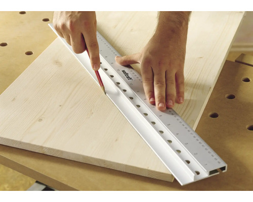 Person, die mit einem Bleistift eine Linie entlang eines Wolfcraft Lineals auf ein Holzbrett zeichnet