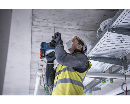 Handwerker bohrt mit einem Bohrhammer ein Loch in die Decke.