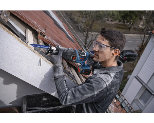 Mann arbeitet mit einer Säbelsäge an einem Dach