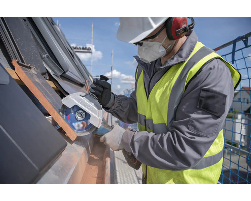 Handwerker mit Winkelschleifer beim Schneiden von Dachziegeln