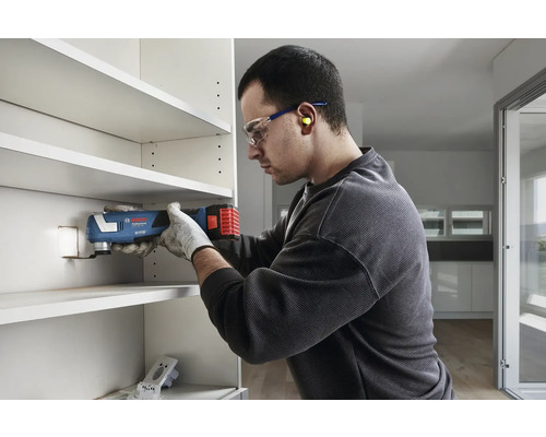 Ein Mann benutzt ein Multifunktionswerkzeug zum Sägen in einem Regalfach.