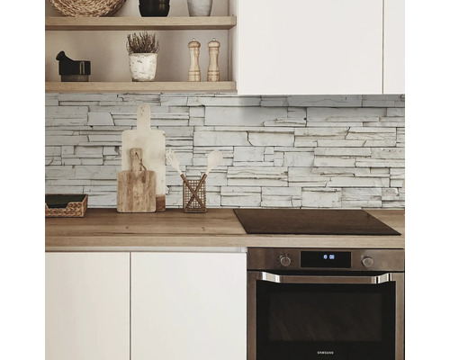 Küchenansicht mit Steinwand, Arbeitsplatte, Spüle und Backofen.