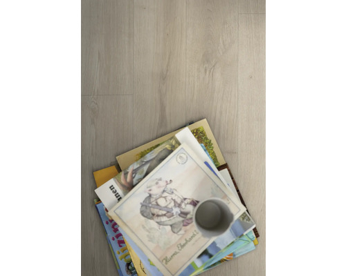 Stapel Kinderbücher und ein Becher auf einem Bodenbelag.