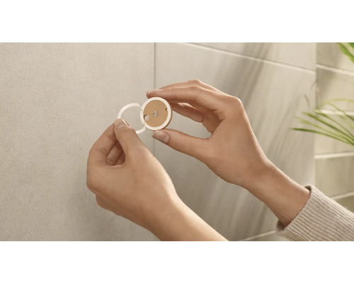 Installation eines runden, selbstklebenden Befestigungselements an einer Wand